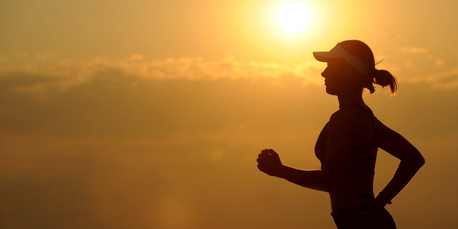 fit woman running at sunset in shape wearing a hat