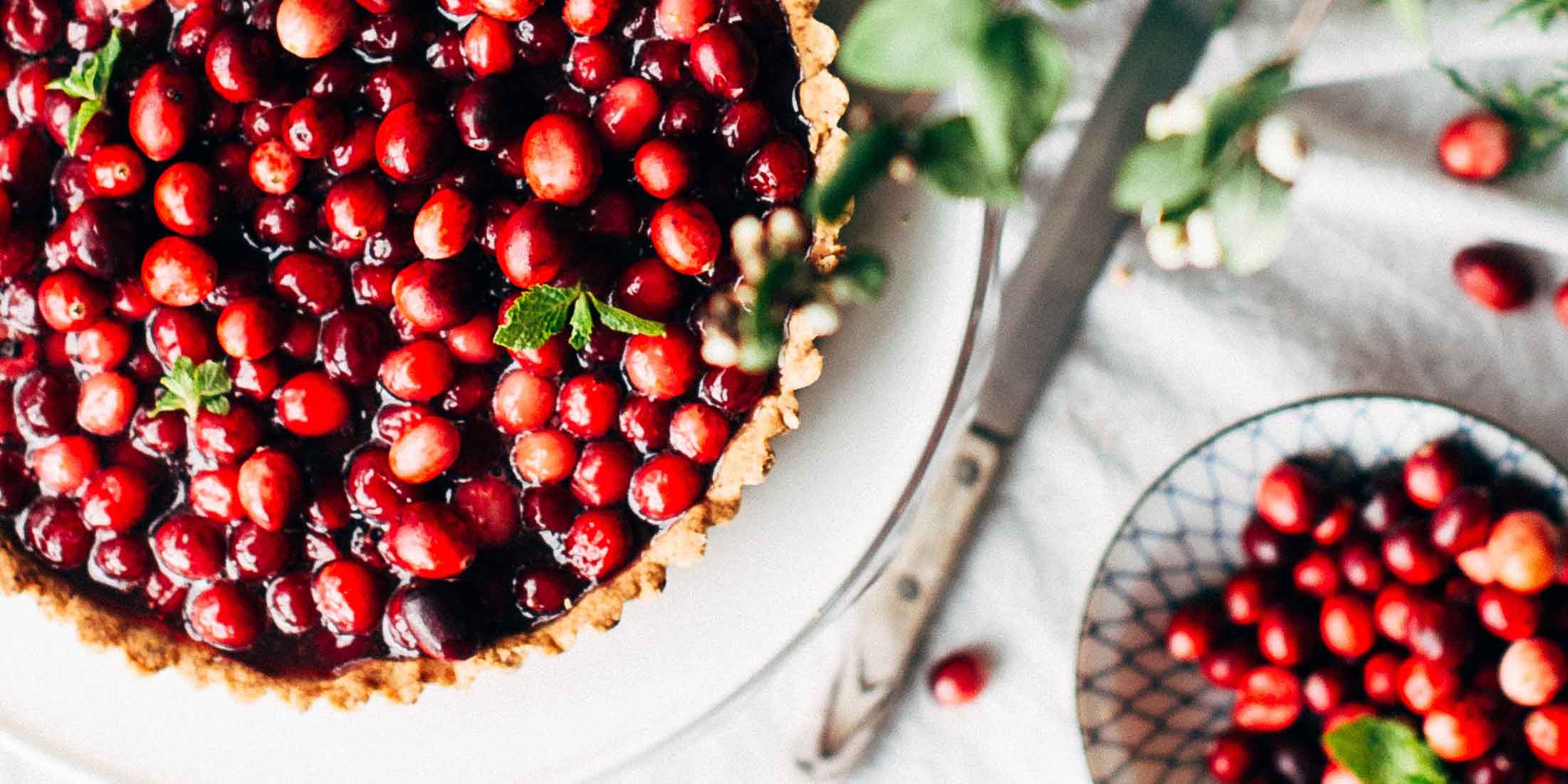Cranberry pie on a table and cranberries in a bowl on the side with flavonols