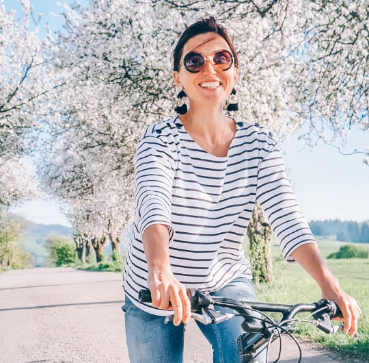 woman smiling happy woman riding her bike sunglasses healthy lifestyle taking personalized supplements sunny day